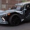 Sleek, futuristic three-wheeled sports car with sharp angles and open cockpit.