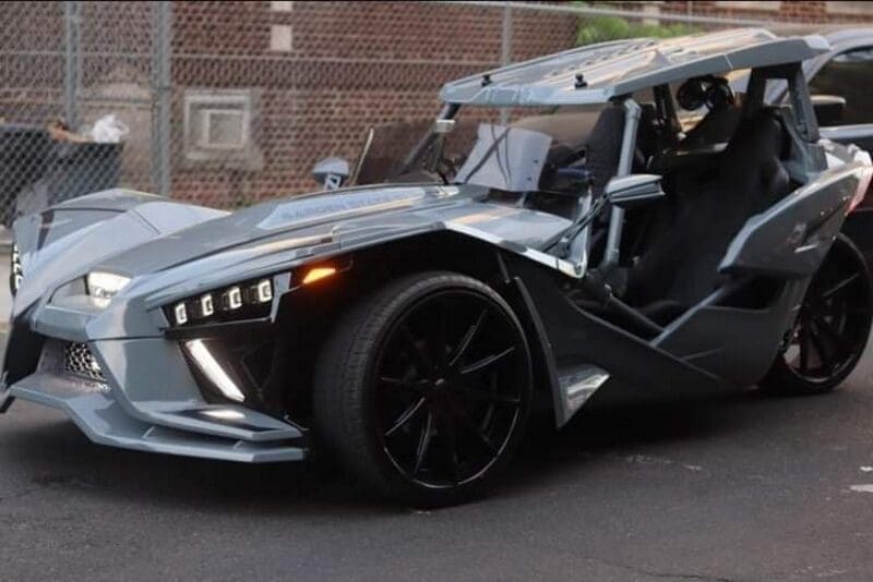 Sleek, futuristic three-wheeled sports car with sharp angles and open cockpit.