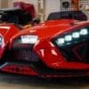 Red Polaris three-wheeled vehicle with futuristic headlights in a garage.