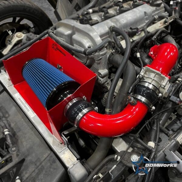Close-up of a red cold air intake system in a car engine bay.