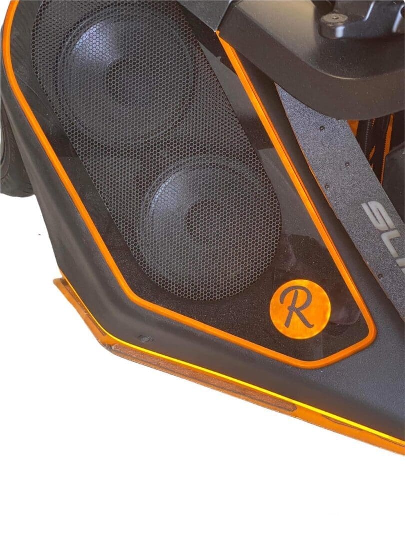 Close-up of a black and orange speaker grille with two visible speakers.