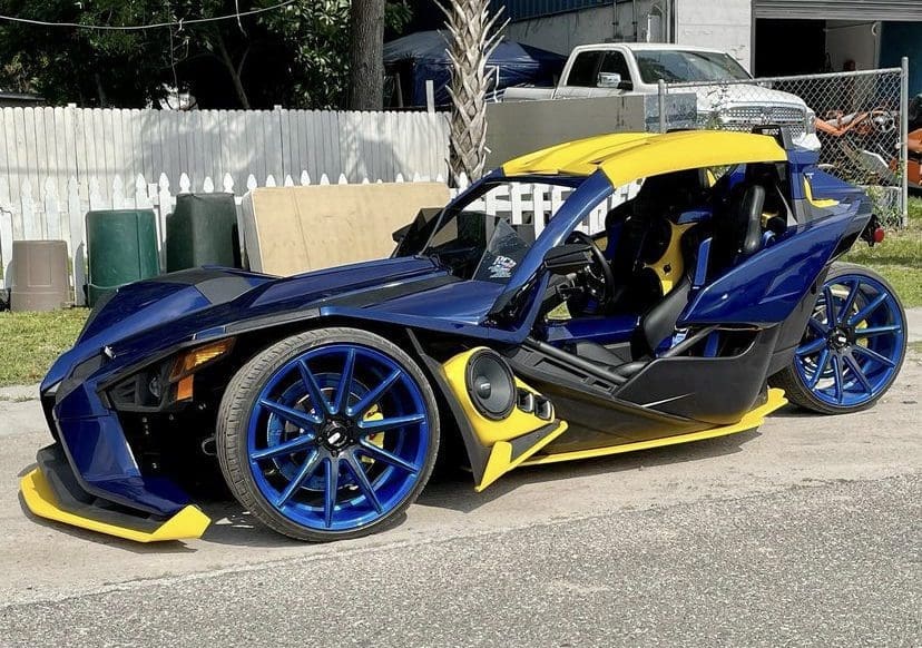 IMG-3208 A customized blue and yellow sports car with unique wheels and a sleek design.