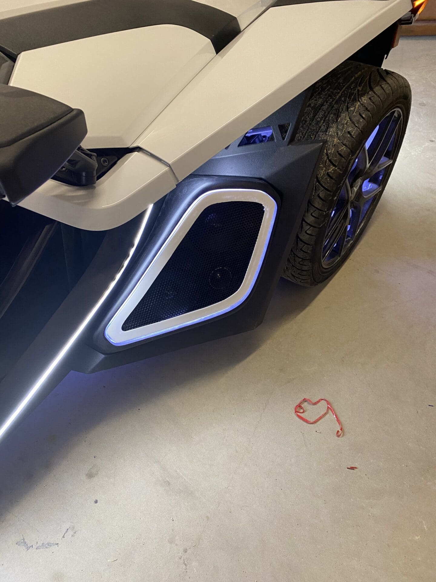 Close-up of a white vehicle's rear side with a unique silver exhaust design.
