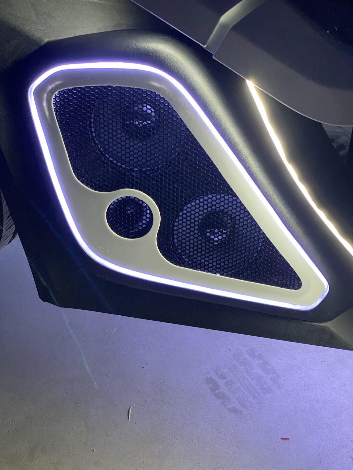 Close-up of a car door panel with illuminated speaker grills.