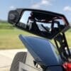 Close-up of a side mirror and part of a sleek vehicle with an open-air design.