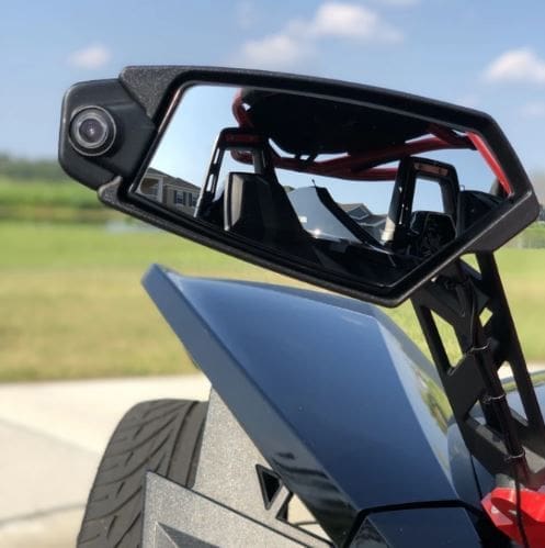 Close-up of a side mirror and part of a sleek vehicle with an open-air design.