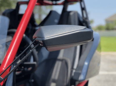 Side mirror on a red off-road vehicle with bucket seats.