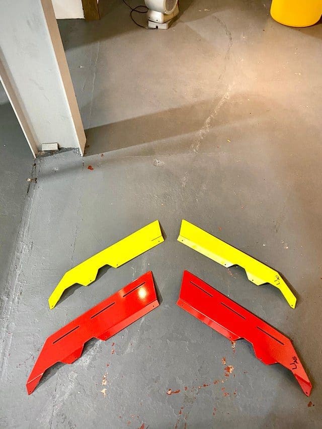 spliters Four colorful plastic car spoiler parts on the floor.