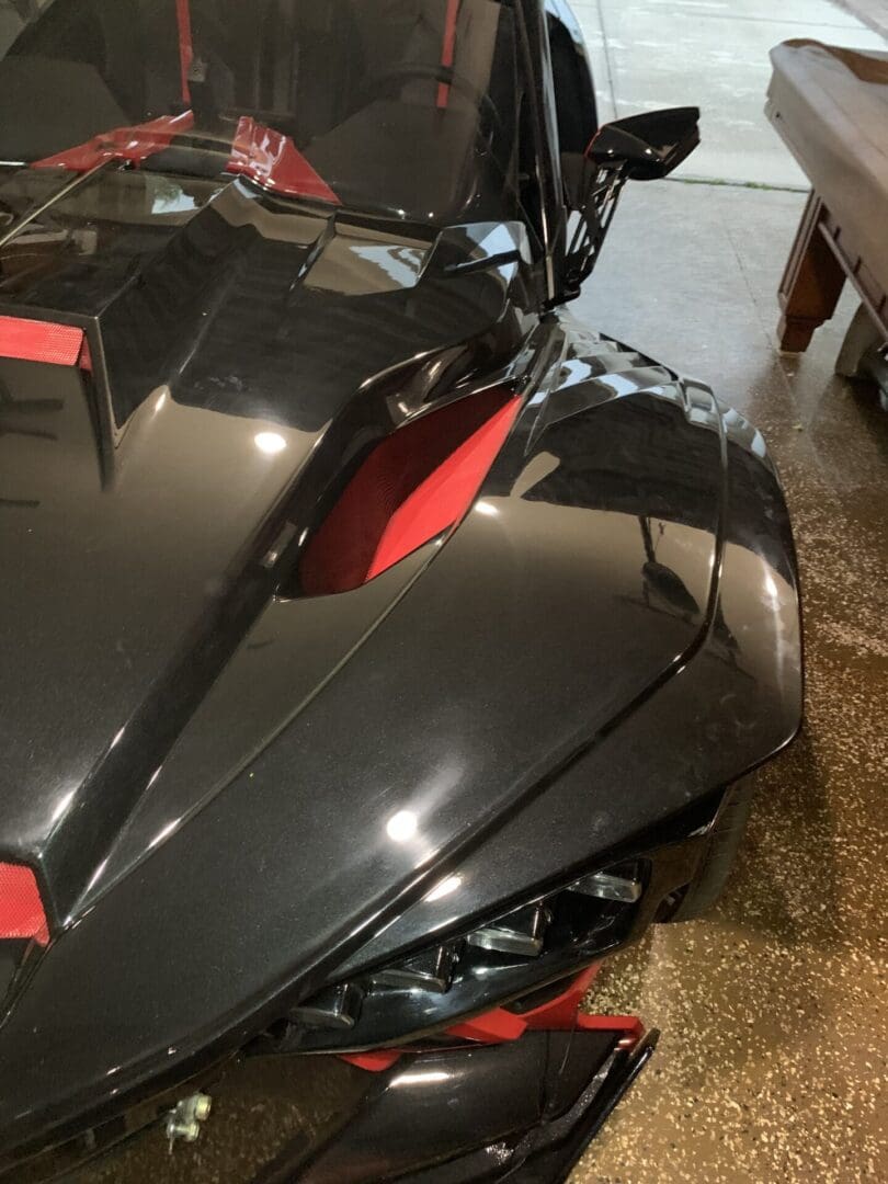 IMG_4367 Close-up of a sleek black and red sports car hood with sharp angles.