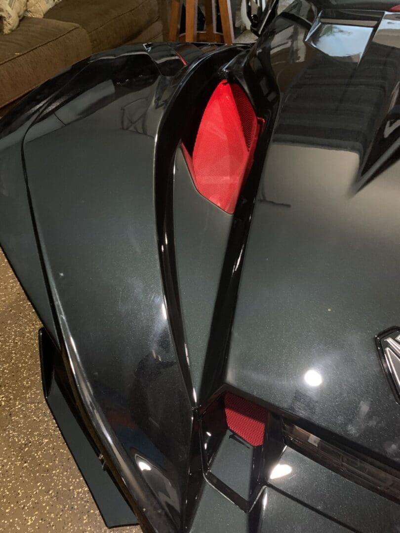 IMG_4371 Close-up of a sleek black sports car's rear with red taillight and aerodynamic design.
