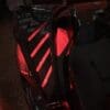 IMG_4373 Close-up of a black car hood with red illuminated vents in a dim garage.
