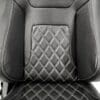 Close-up of a black leather car seat with diamond-pattern stitching.