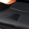 Close-up of a black textured car seat with orange accent.
