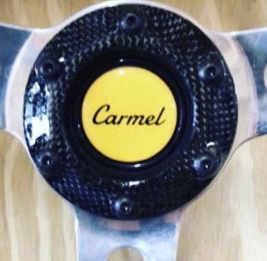 IMG_6973 Close-up of a car steering wheel center with 'Carmel' logo.
