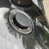 IMG_6978 Close-up of a black car's fuel cap on a shiny surface.