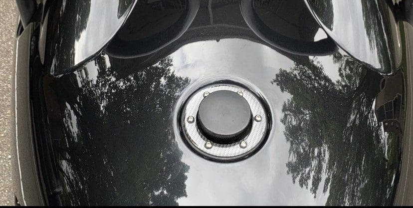IMG_6979 Close-up of a shiny black motorcycle fuel tank with a chrome fuel cap.