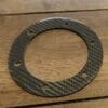 IMG_6980 Carbon fiber circular gasket with six holes on a wooden surface.