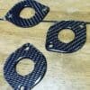 IMG_6986 Three black carbon fiber washers with different shapes on a wooden surface.