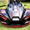 IMG_7279 A sleek black and red Polaris Slingshot parked on grass.