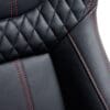 5ea1bc7b-0c80-4b16-a17f-d9dd8be00461 Close-up of black leather car seat with red stitching.