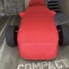 IMG_8046 A small race car covered in a red cloth in a parking space.