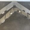 Metal bracket with multiple holes on a concrete surface.