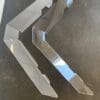 Two large metal brackets on a concrete floor.