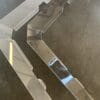 Two shiny metal hinges on a brown carpet surface.