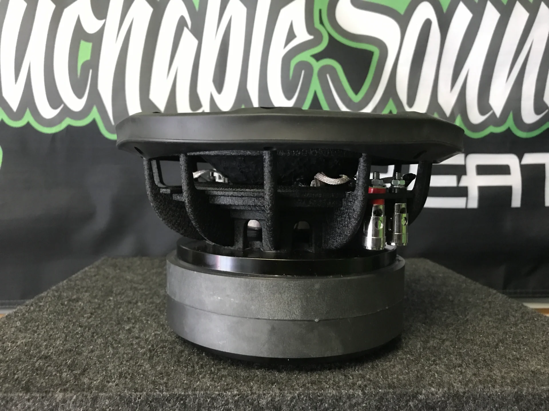 image_e91f57da-95af-4561-86d2-144e7a925dc4 Side view of a black subwoofer speaker on a gray surface.