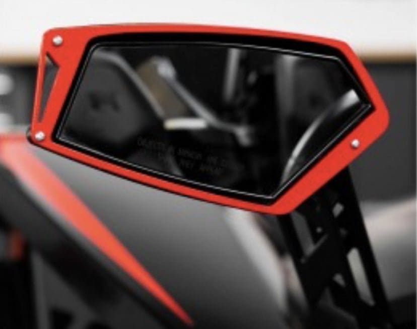 IMG-1700 Close-up of a red side mirror on a vehicle showing part of the interior.