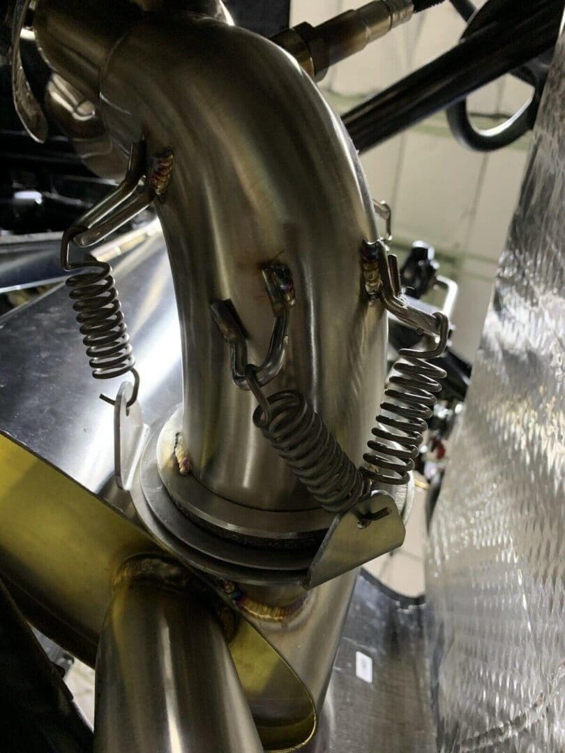 Close-up of a metal pipe with attached springs in an industrial setting.