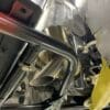 Close-up of metal pipes and engine components under a vehicle.