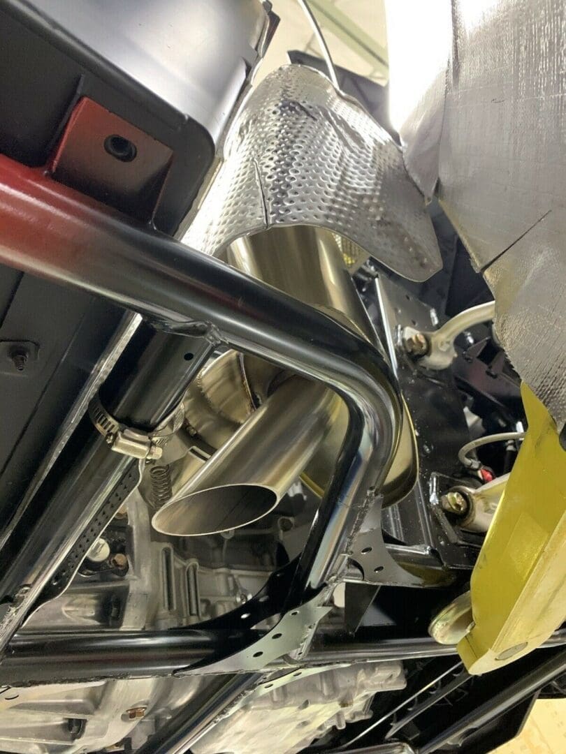Close-up of metal pipes and engine components under a vehicle.