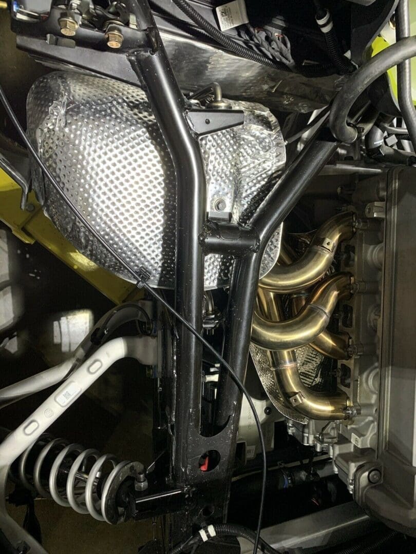 Close-up of a car engine's exhaust manifold and suspension components.