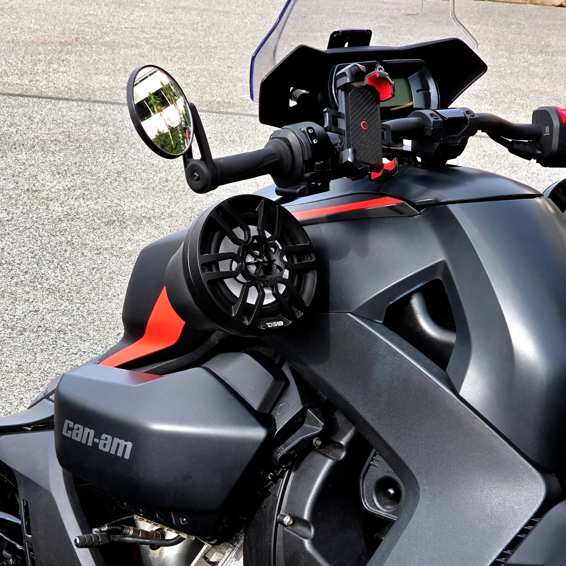 EN-JS6-Package-2000X2000-3_3000x Close-up of a black and orange Can-Am motorcycle handlebar and side mirror.