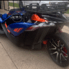 A sleek blue and orange three-wheeled motorcycle parked on a driveway.