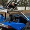 img_0864-2 Man driving a blue dune buggy with a roll cage and open roof.