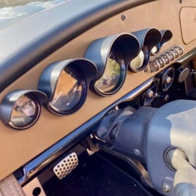 Close-up of vintage car dashboard with classic gauges and steering wheel.